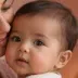 A baby with dark hair, held close